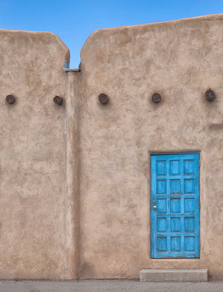 brown adobe building containing a blue door